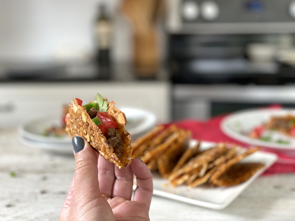 holding keto hard taco shell with ground beef inside 