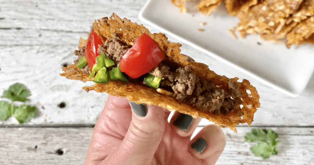 holding keto hard taco shell filled with ground beef