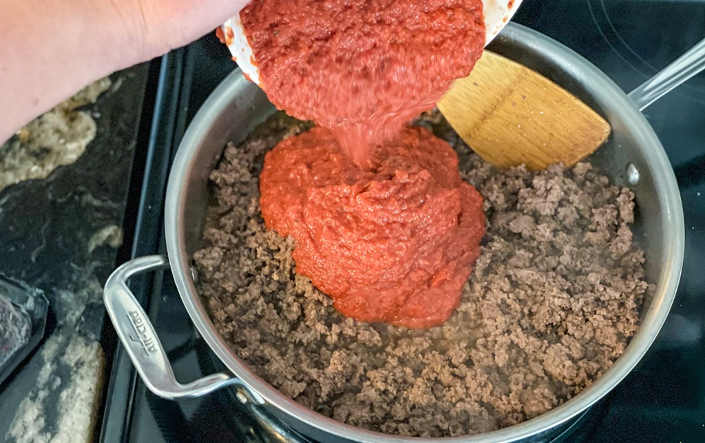 adding marinara sauce to ground beef