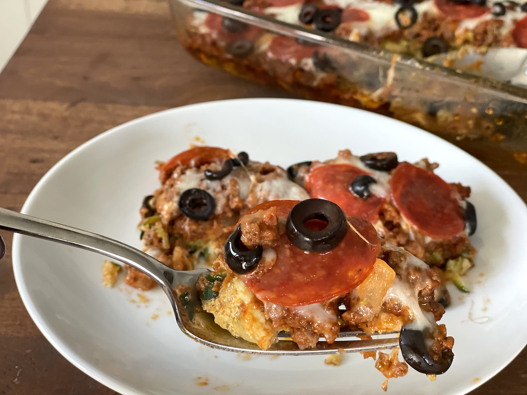 taking bite of keto pizza casserole on plate 