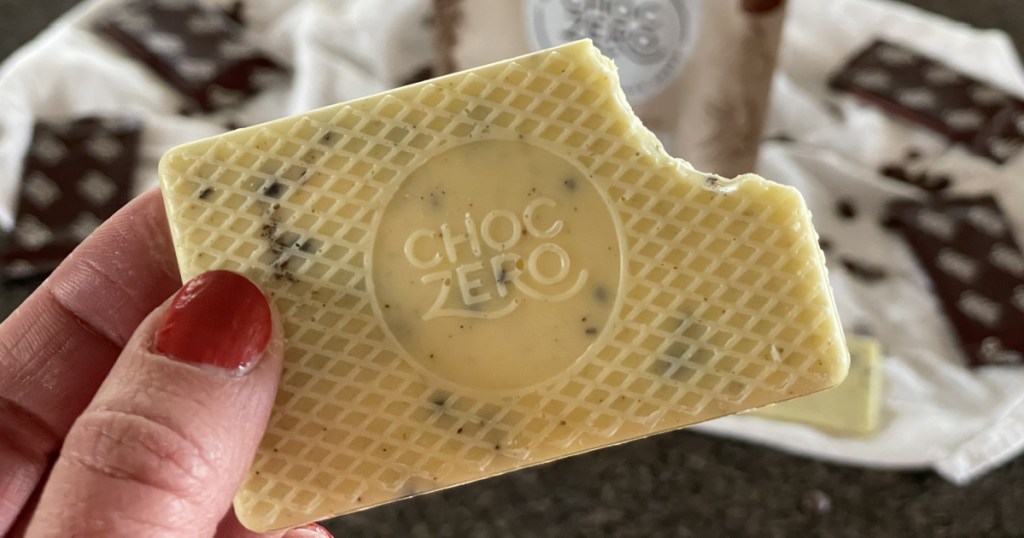 ChocZero Keto Bark holding cookies & cream with a bite out of it