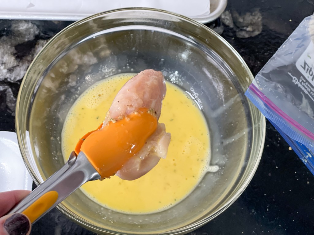 dipping a chicken strip in egg wash