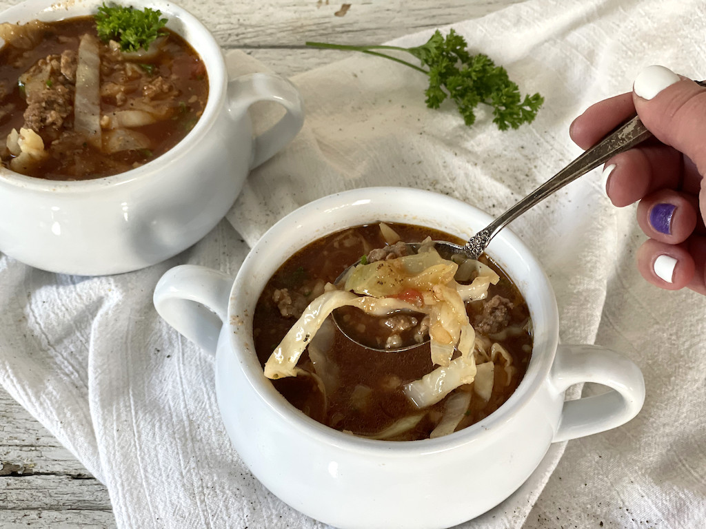 taking spoonful of keto Crockpot cabbage roll soup in bowl 