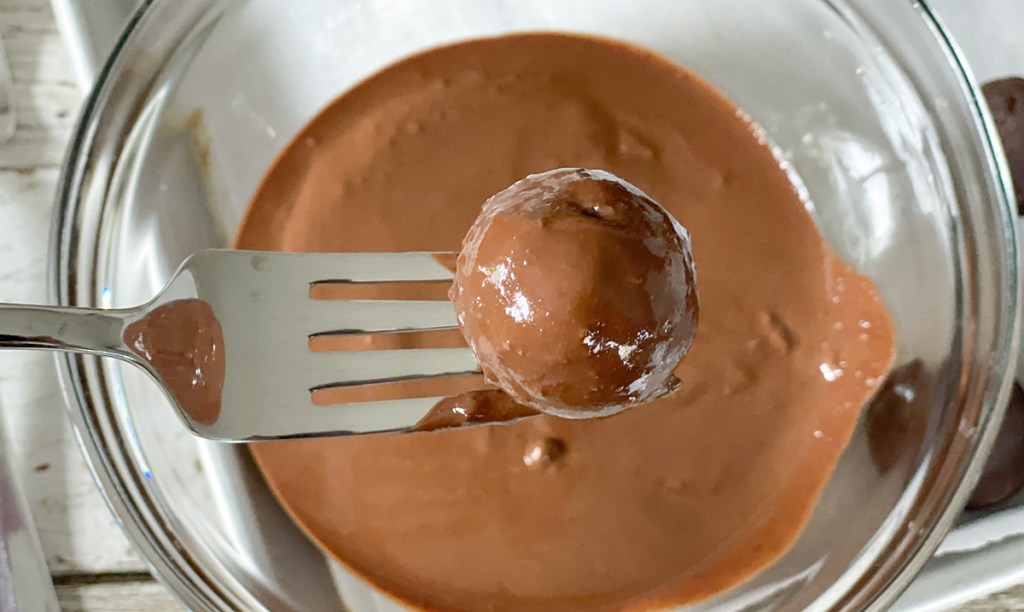 dipping brownie ball into melted chocolate