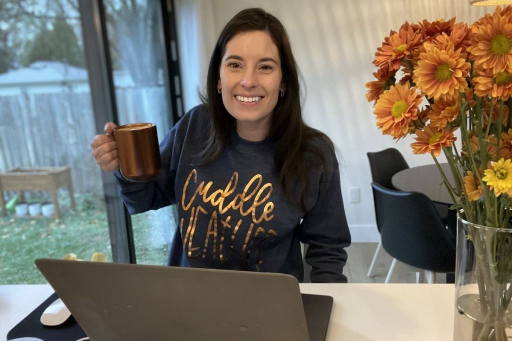 woman wearing a christmas sweater and holding a cup of coffee