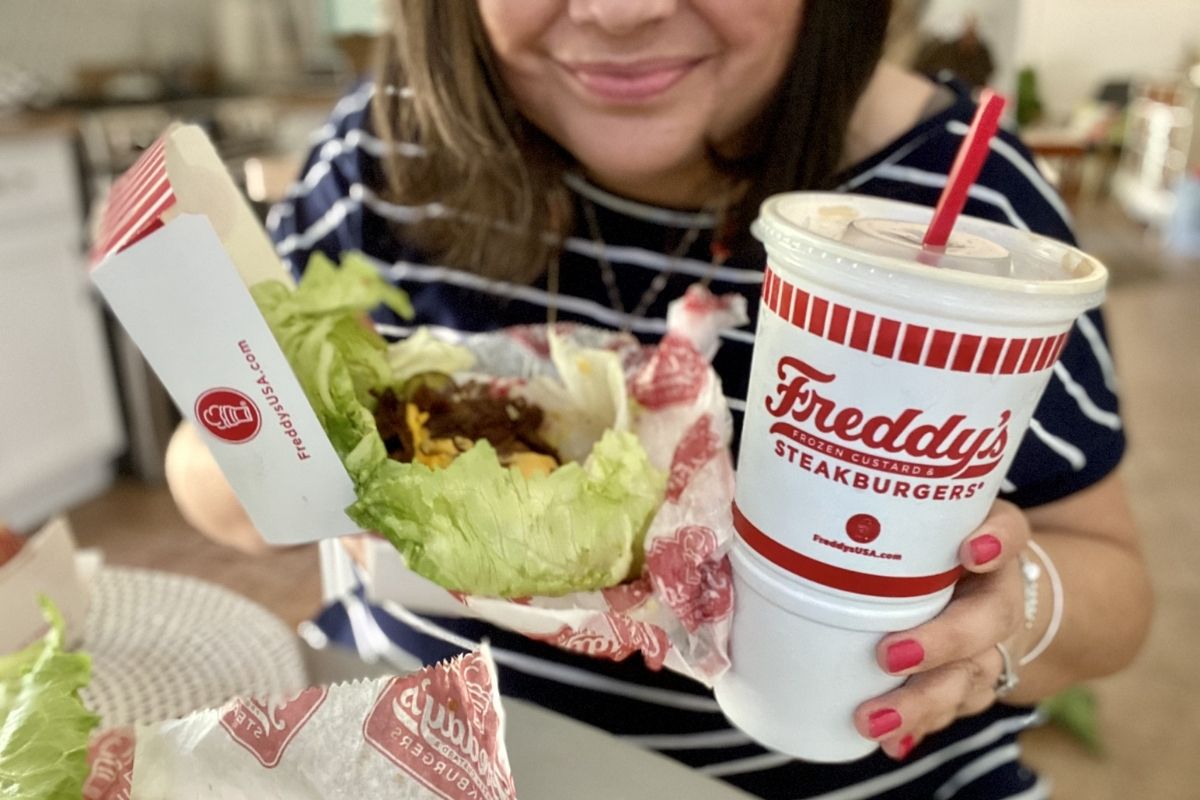 woman holding a steakburger and soda from Freddy's keto menu with lettuce wrapped items