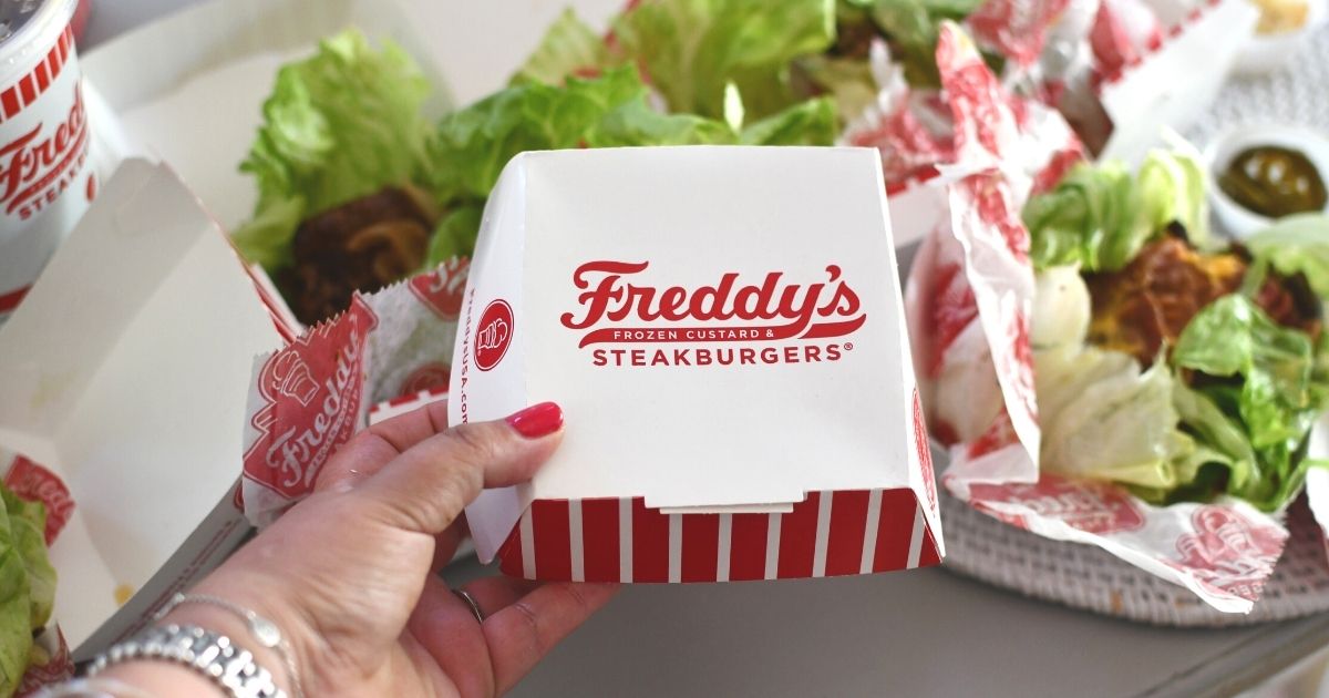 holding Freddy's Steakburger container in front of lettuce wrapped keto sandwiches from the Freddy's keto menu
