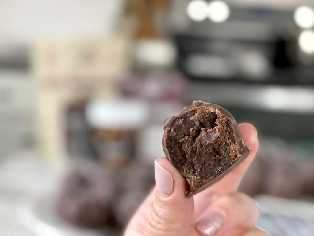 holding keto chocolate truffle with bite taken out of it