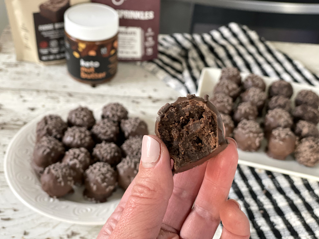 holding up keto chocolate truffle with chocolate truffles in the background
