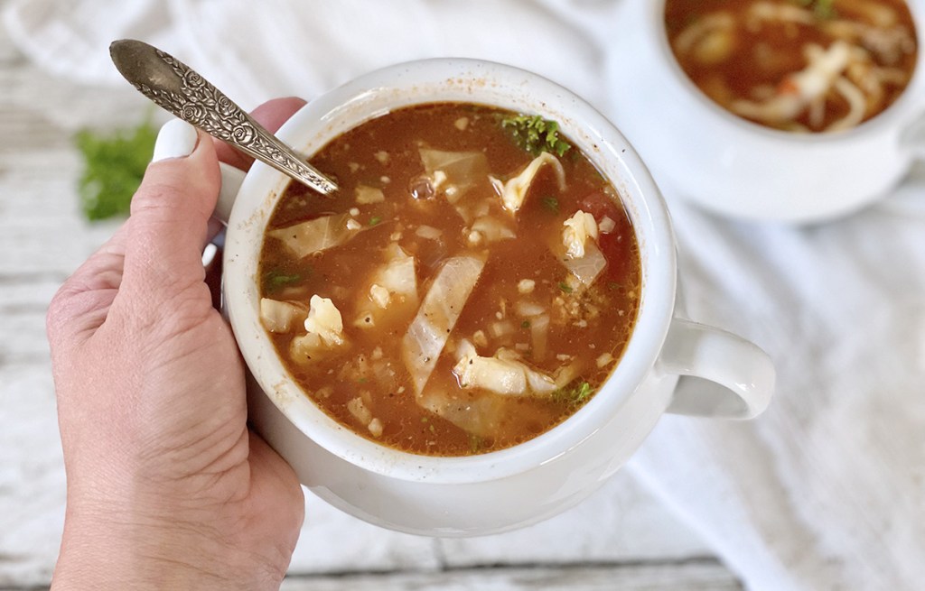hand holding bowl of keto cabbage roll soup