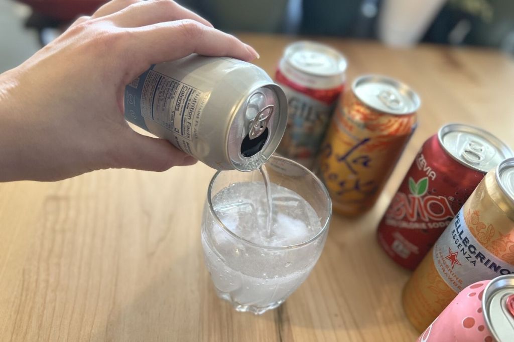 pouring a can of sparkling water into a glass