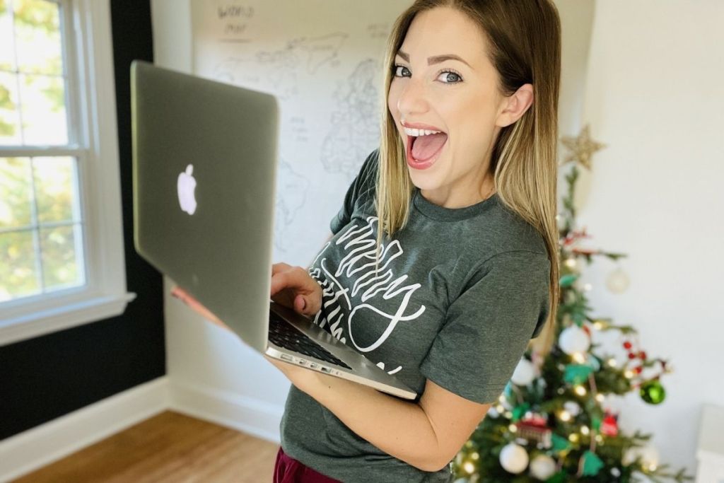 woman holding a laptop in front of a Christmas tree