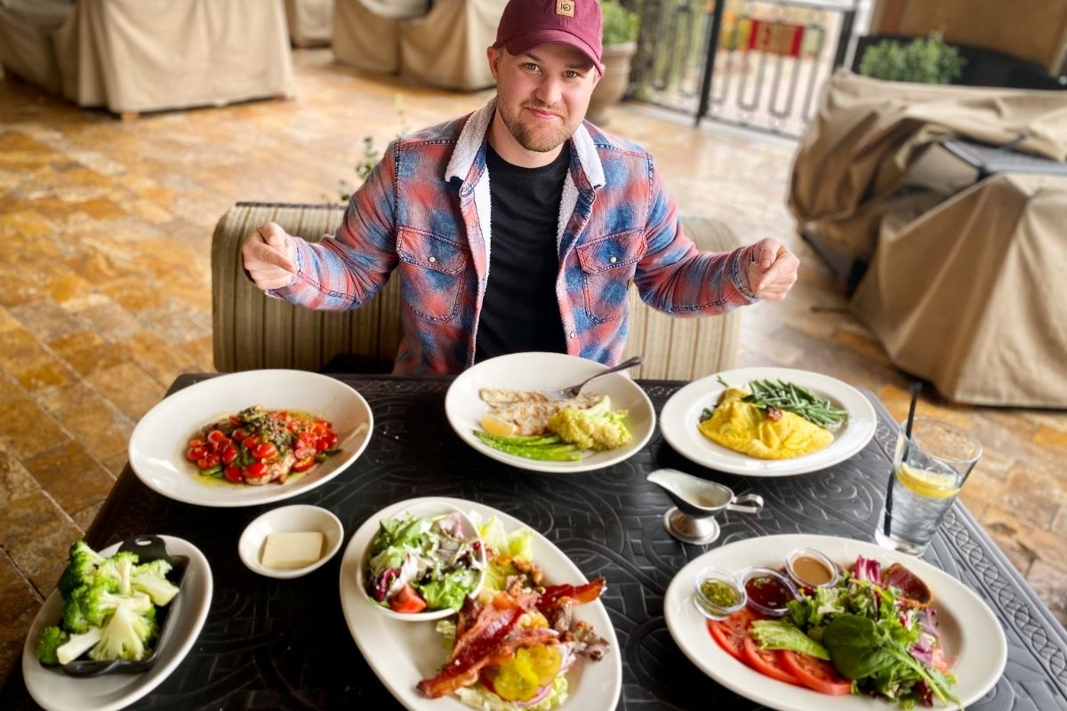 man sitting in front of keto dinner dishes at the Cheesecake Factory