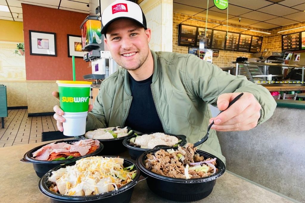 man sitting in Subway with four different salad bowls