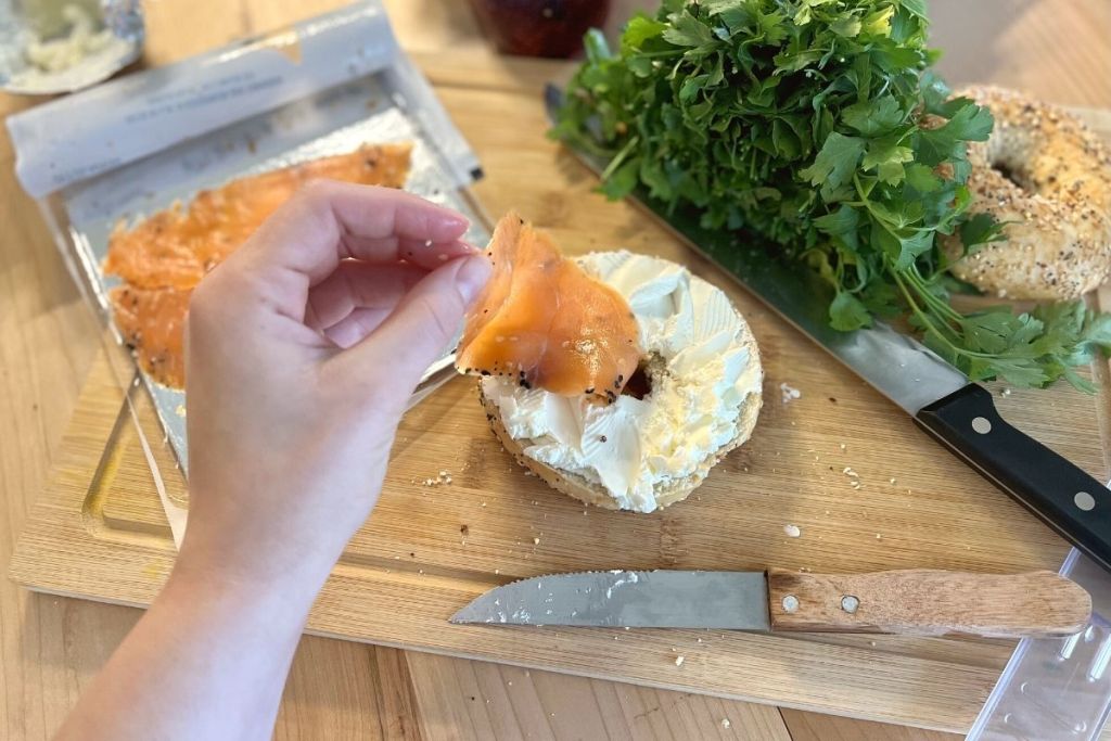 placing a slice of Trader Joe's Everything but the Bagel salmon on a keto bagel with cream cheese