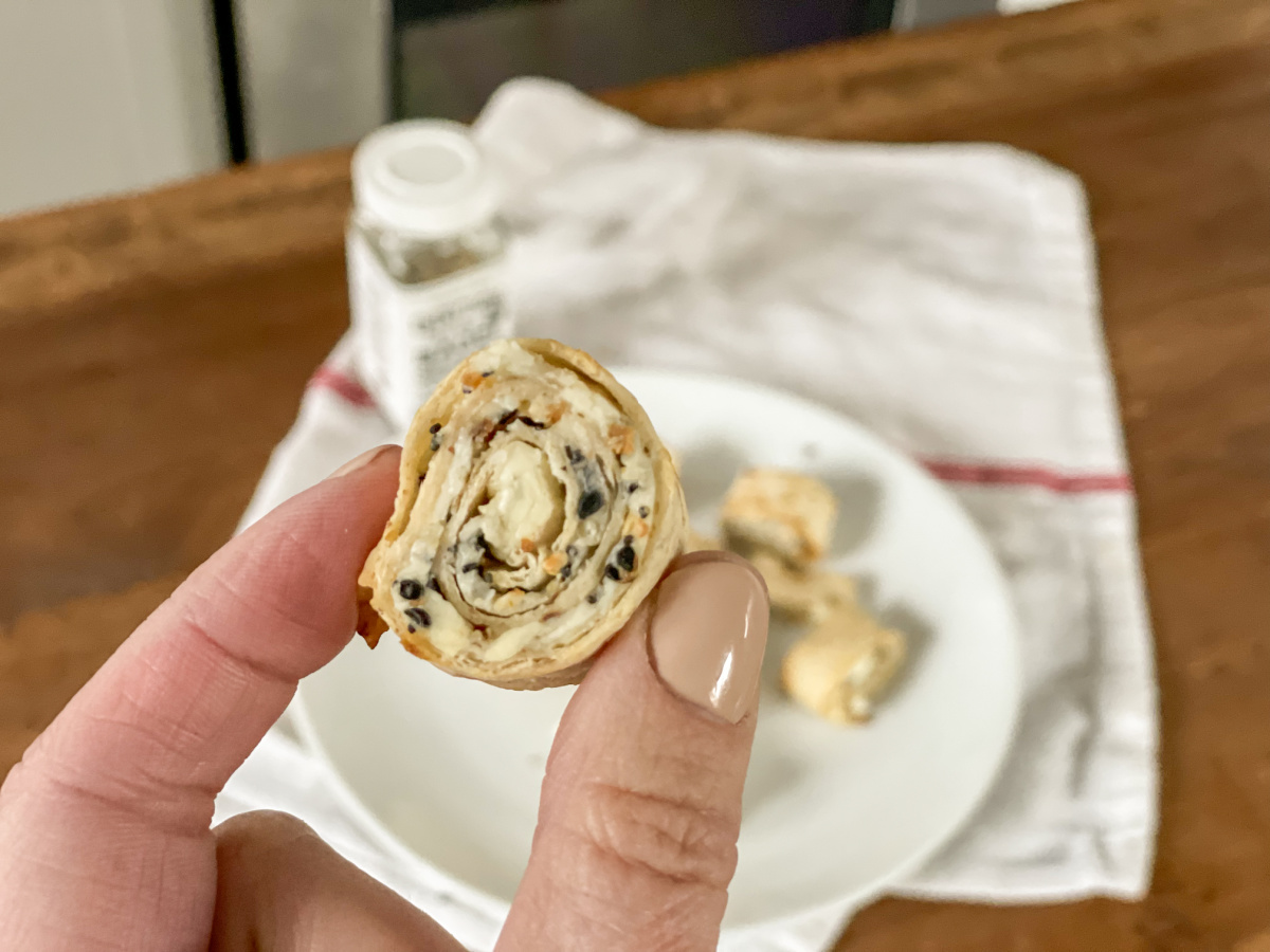 holding a cooked Everything Bagel keto tortilla roll ups