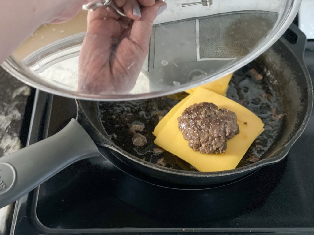 putting a lid on a skillet with a burger in it