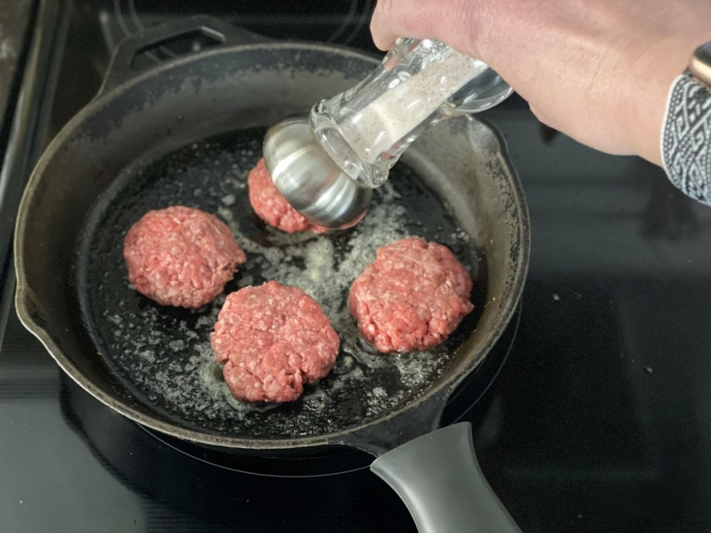 salting hamburger patties in a skillet 
