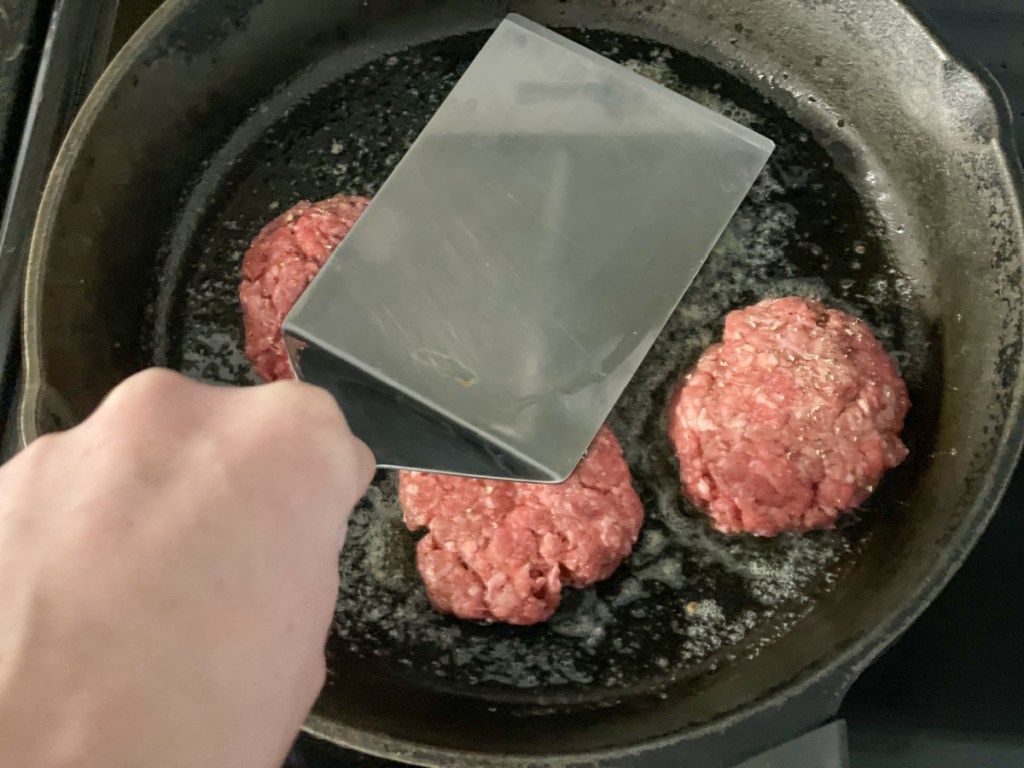 flattening hamburger patties with a spatula 