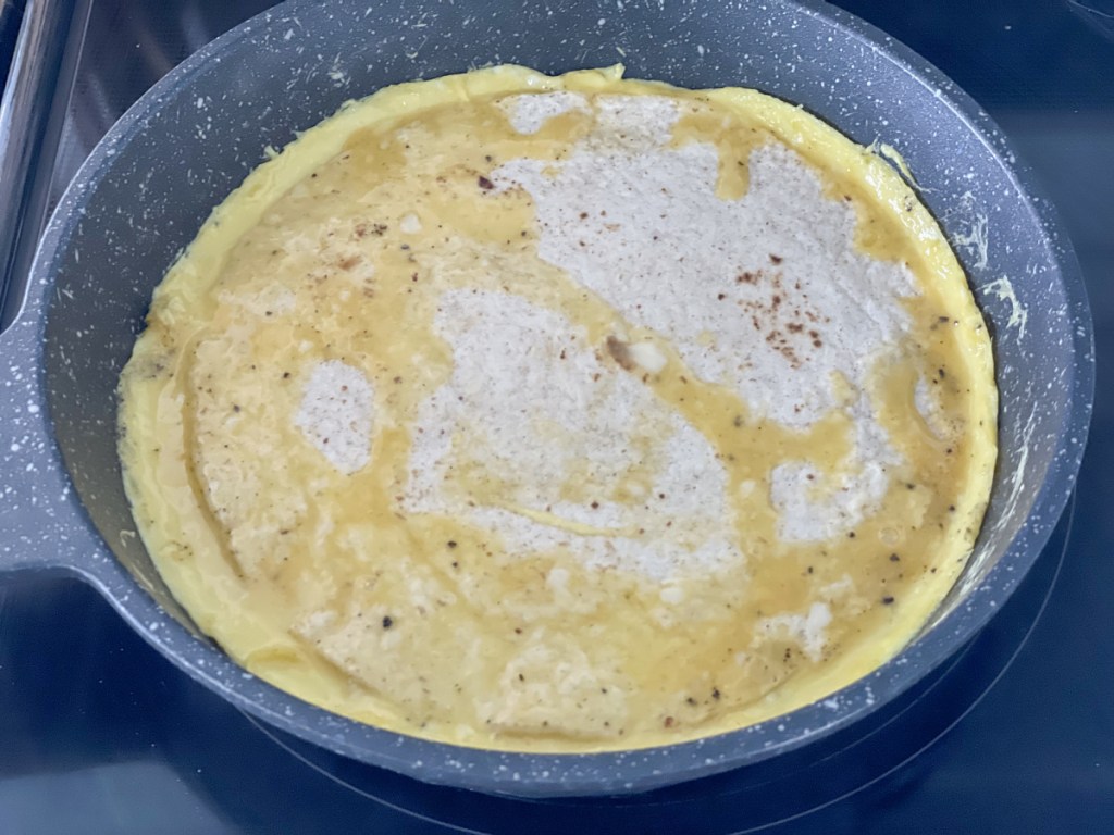 eggs with a tortilla cooking in a skillet 