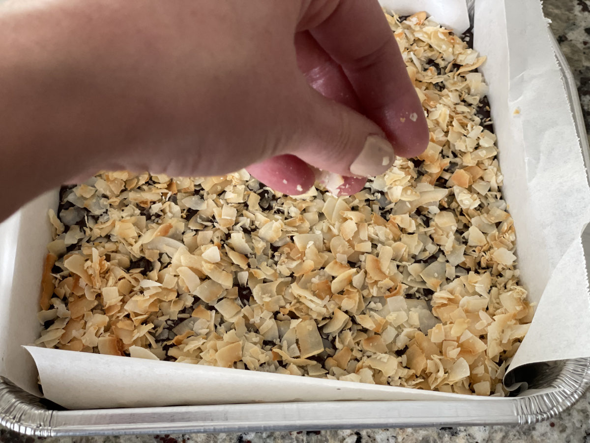 adding coconut flakes to a coconut milk dessert