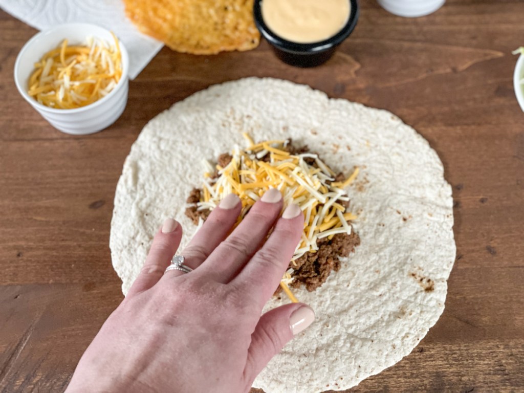 ground beef and cheese on a tortilla for Keto crunchwrap supreme 