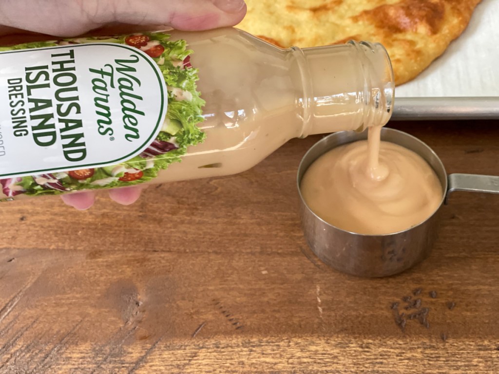 pouring walden farms thousand island dressing into a measuring cup