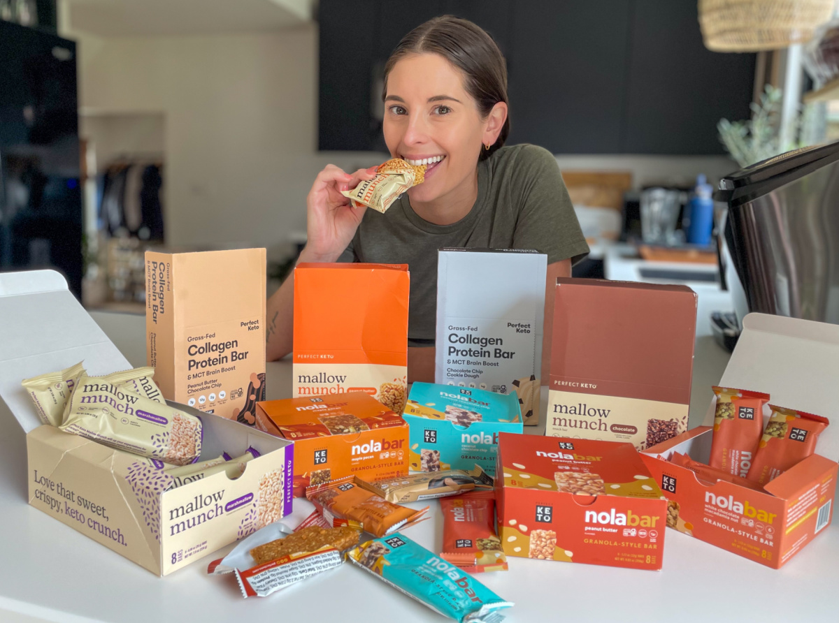 Woman eating and surrounded by Perfect Keto bars