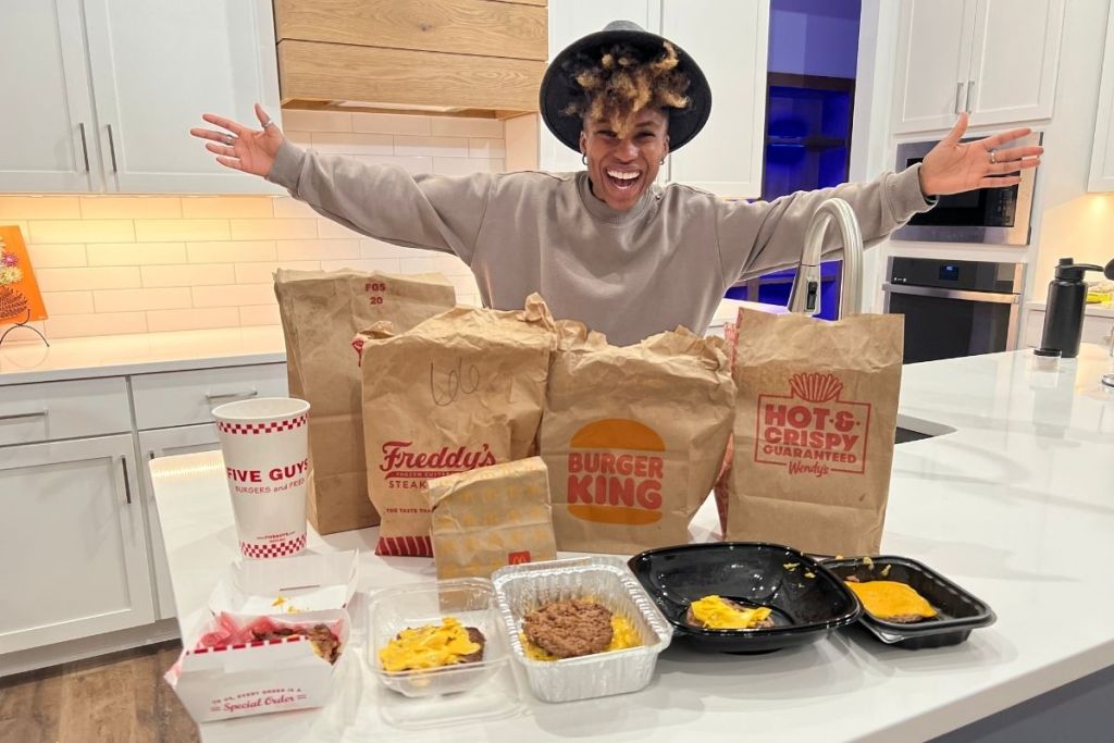 woman standing over a counter with keto burgers from different fast food restaurants