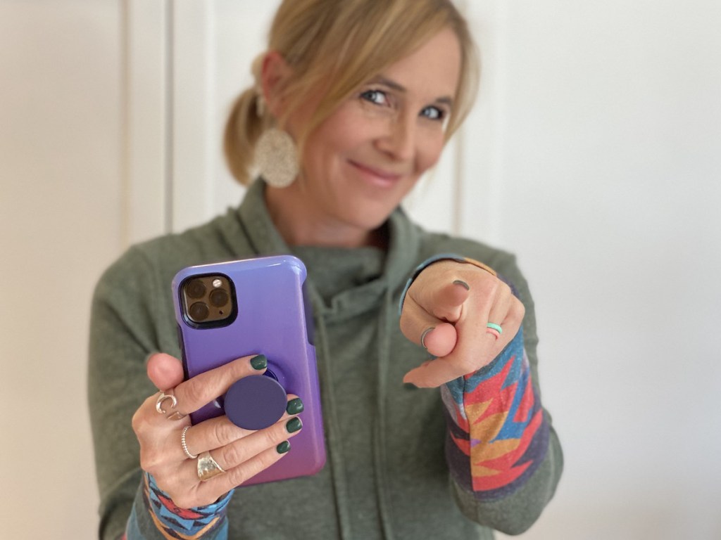 woman holding purple popsocket phone pointing at camera
