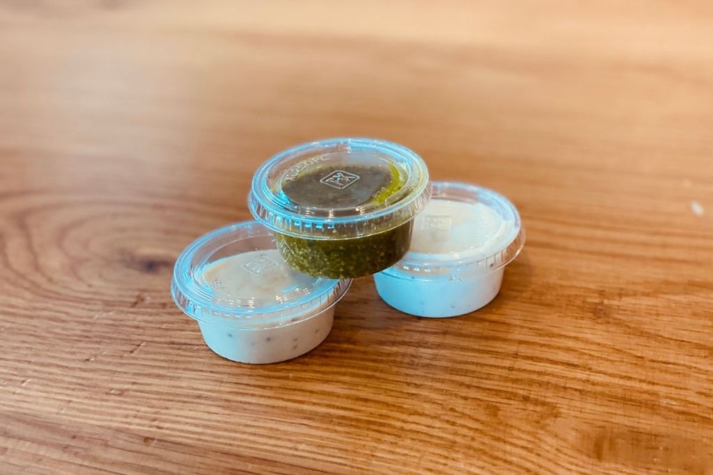 three small pizza sauce containers on table
