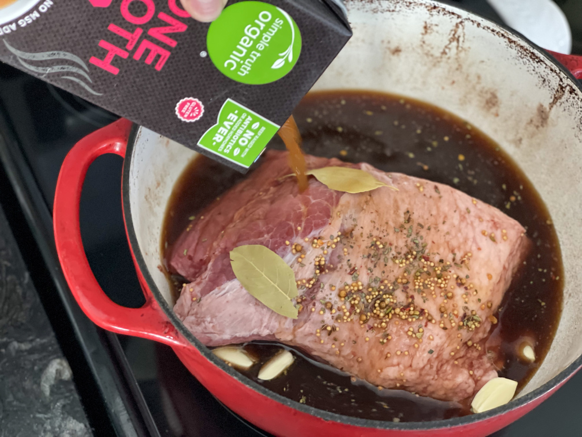 adding bone broth to a dutch oven with keto corned beef roast