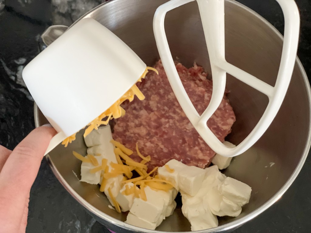 adding shredded cheese to a mixing bowl