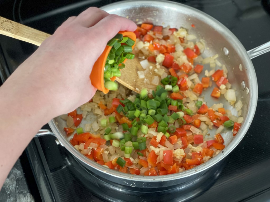 adding green onions to a skillet 