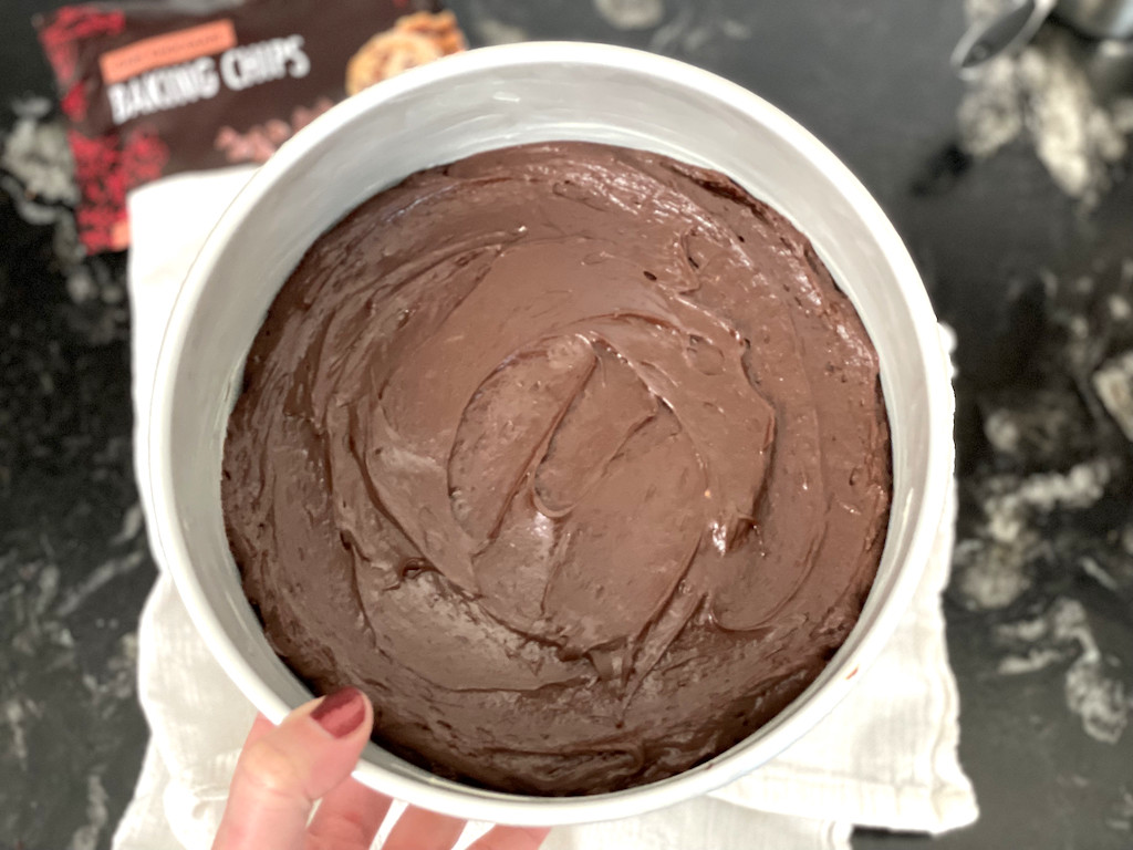 holding keto flourless chocolate cake in pan 
