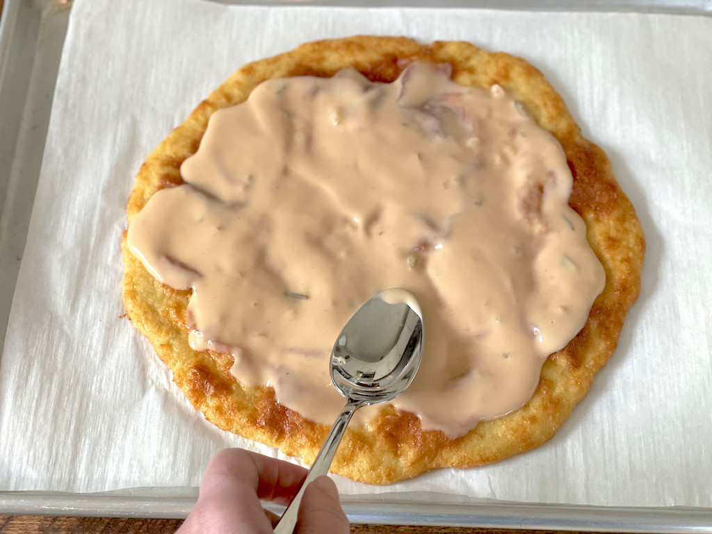 spreading thousand island dressing on keto pizza 