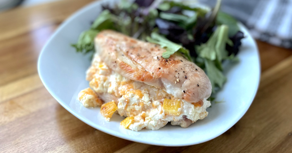 cream cheese stuffed chicken breast on plate with salad 