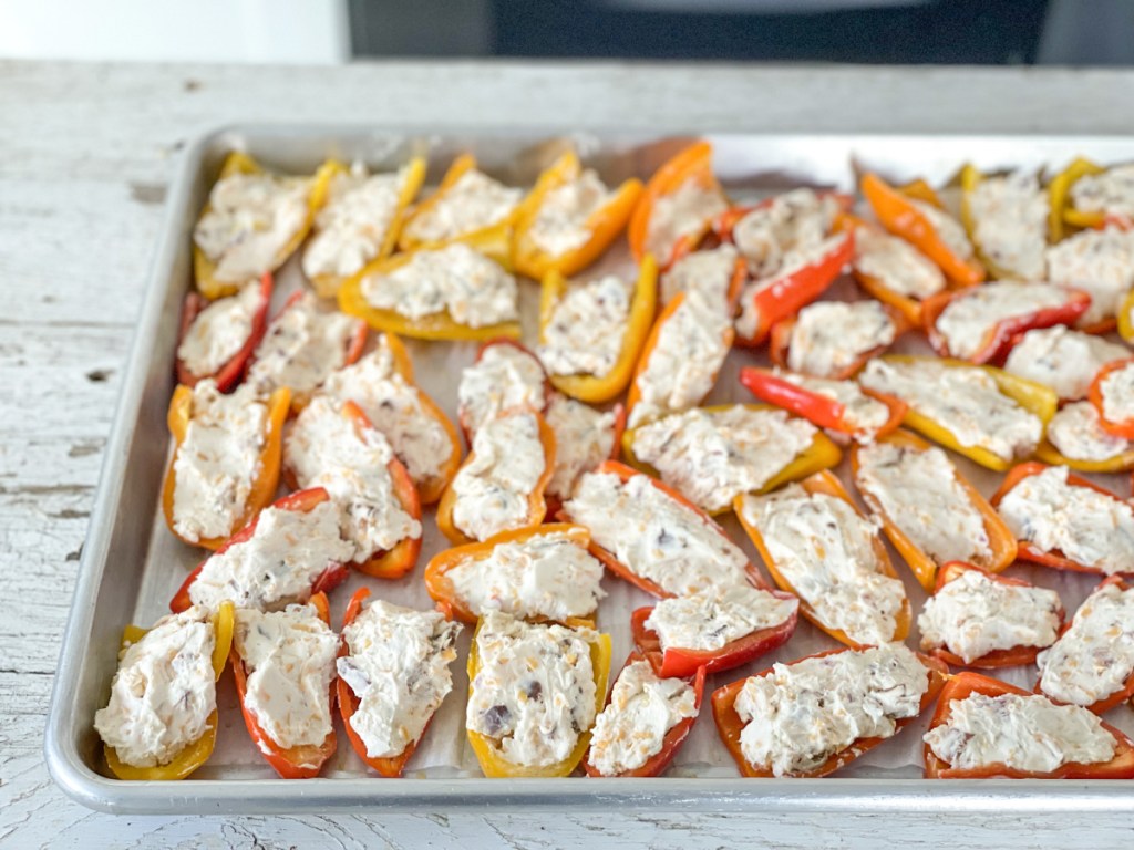 mini peppers stuffed with cream cheese on a baking sheet