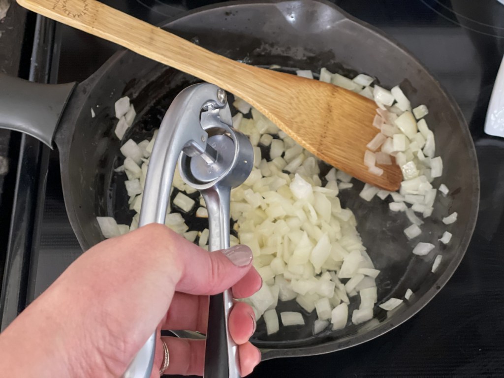 adding garlic to sauted onions in a skilet