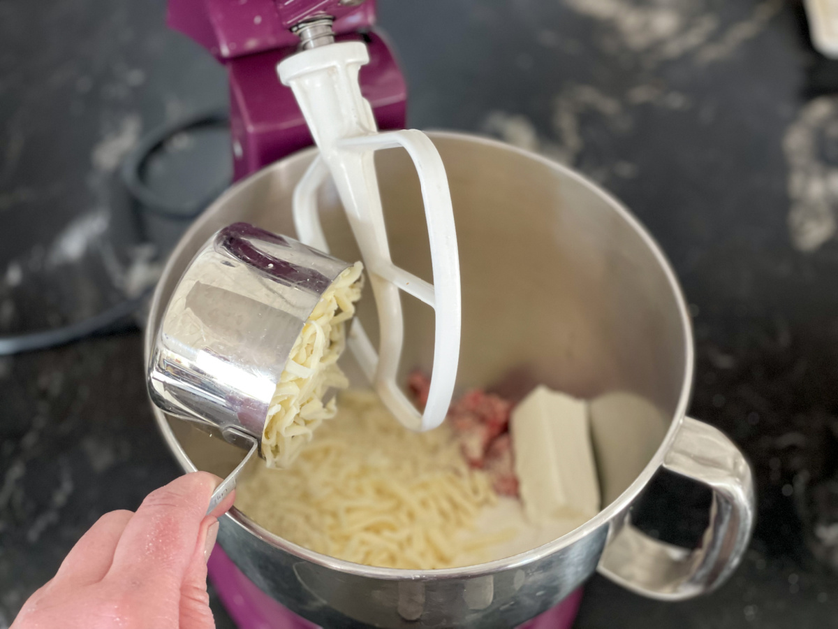 adding shredded cheese to mixer