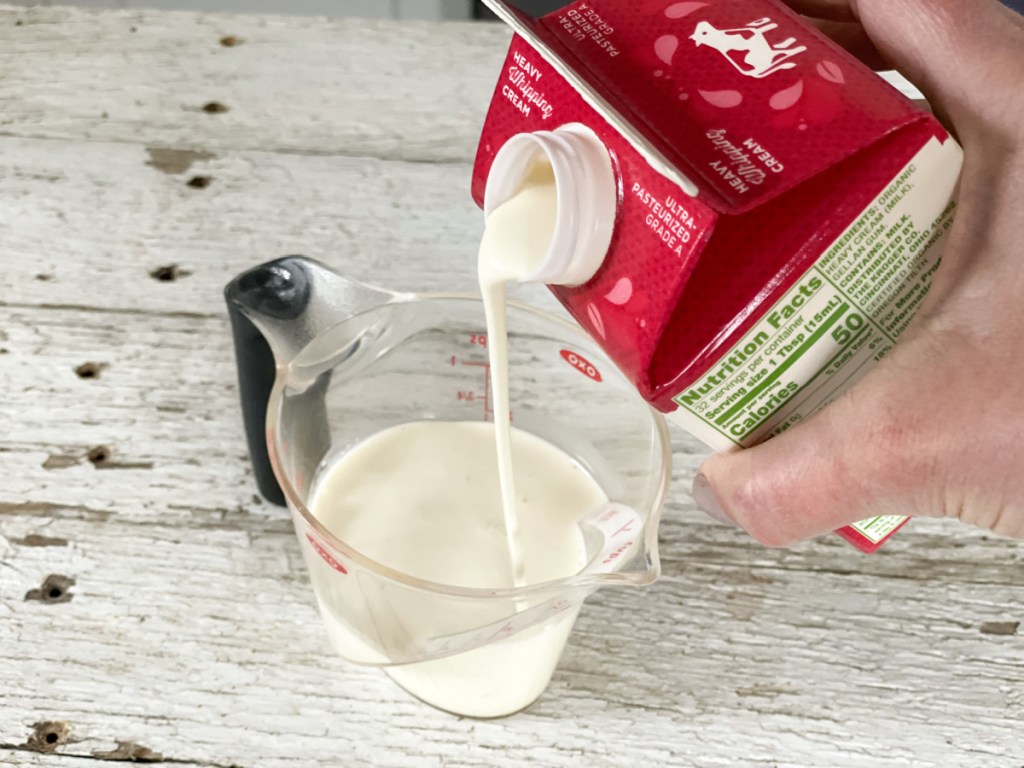 pouring keto whipped cream into a measuring cup