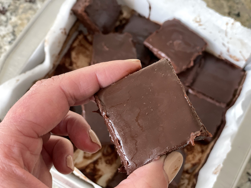 holding piece of chocolate keto fudge 