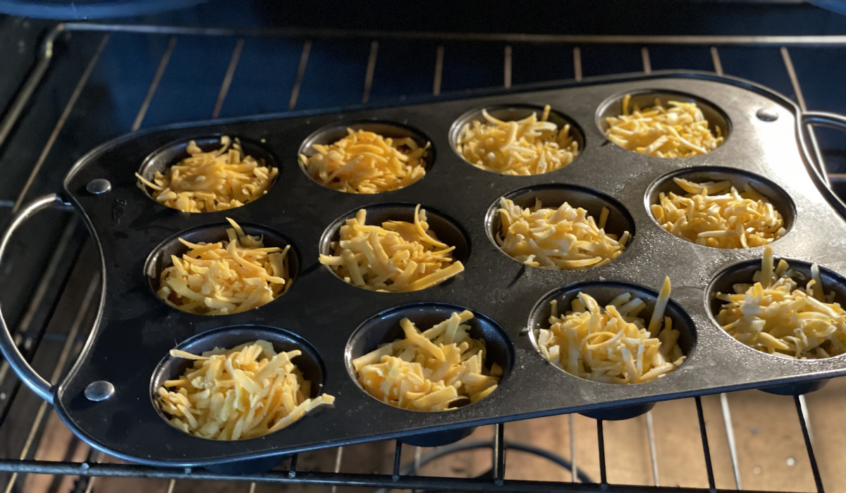 muffin tin with cheese pickle chips in the oven