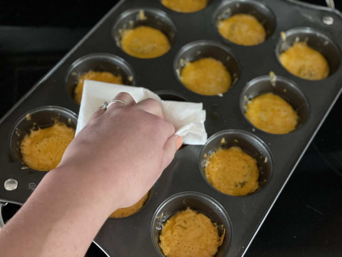 patting grease off cheese pickle chips with a paper towel