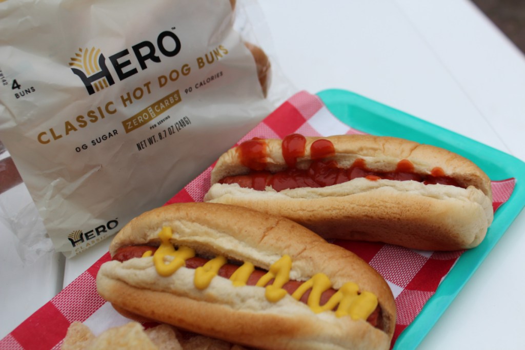 a package of Hero Hot dog buns next to a tray of prepared hot dogs