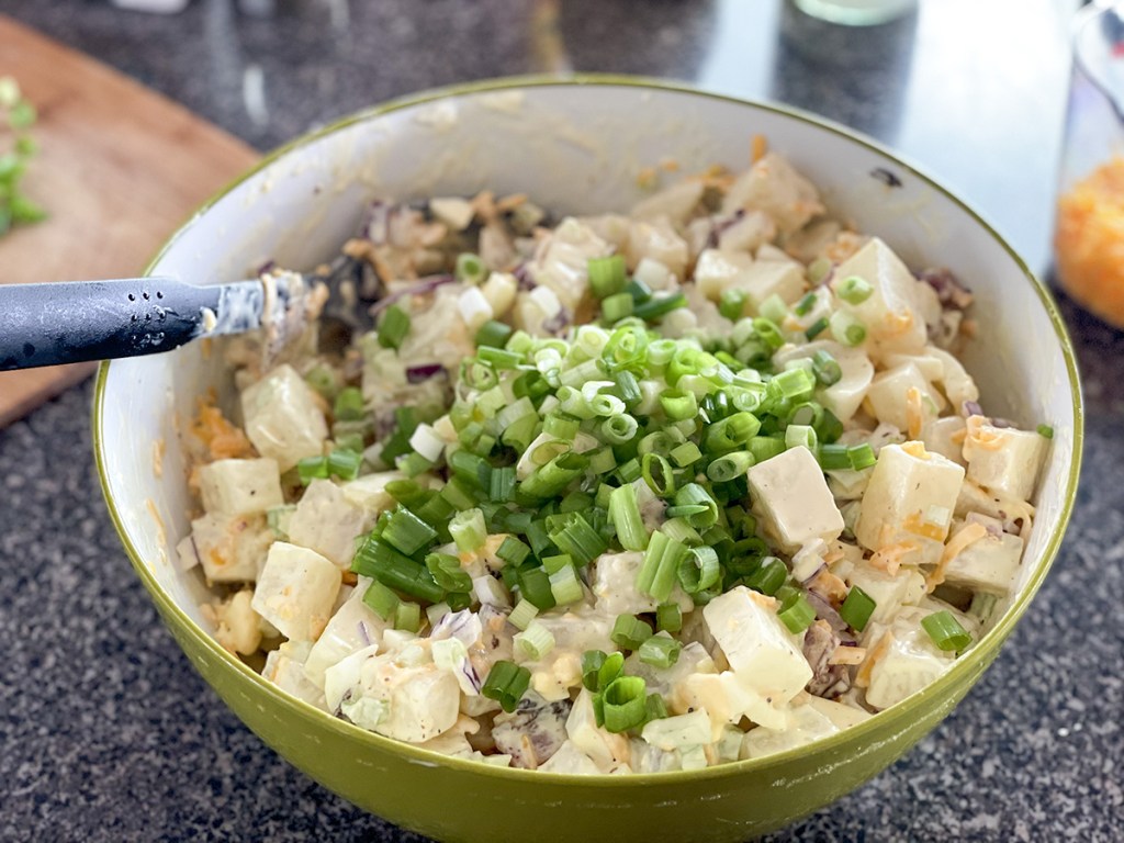 adding green onions to jicama salad 