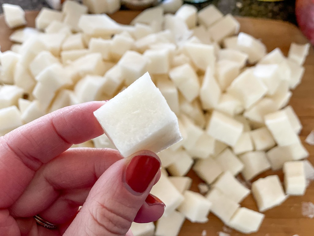 jicama cut into cubes, holding a piece