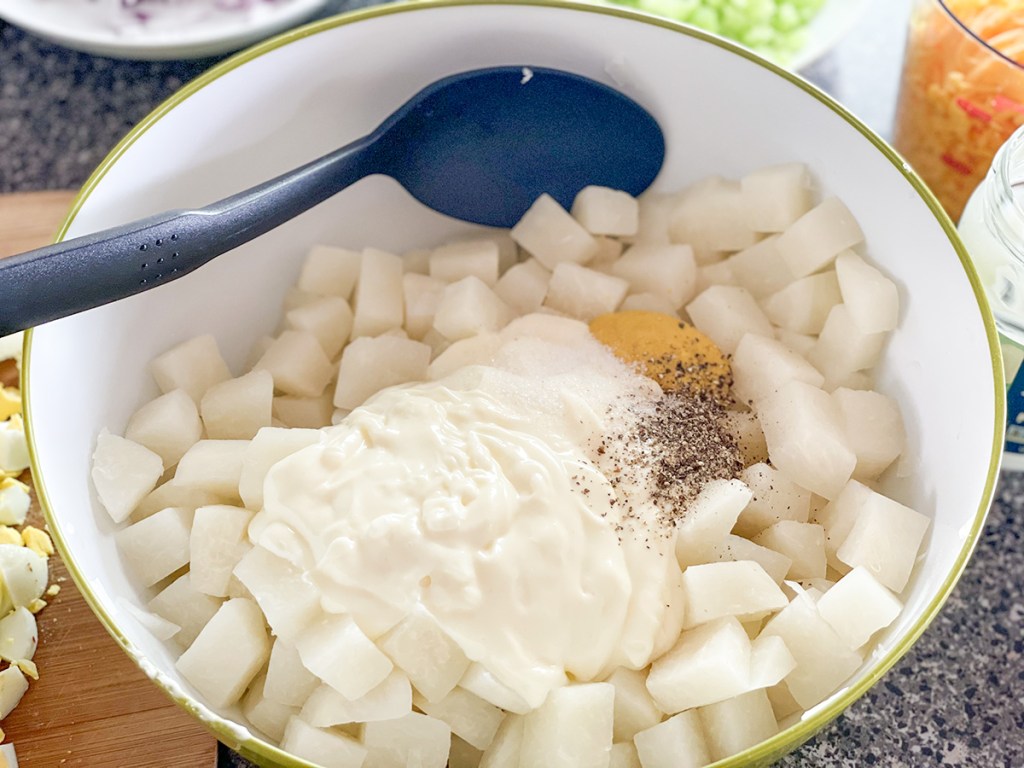 adding mayonnaise, mustard, and seasonings to cooked jicama 