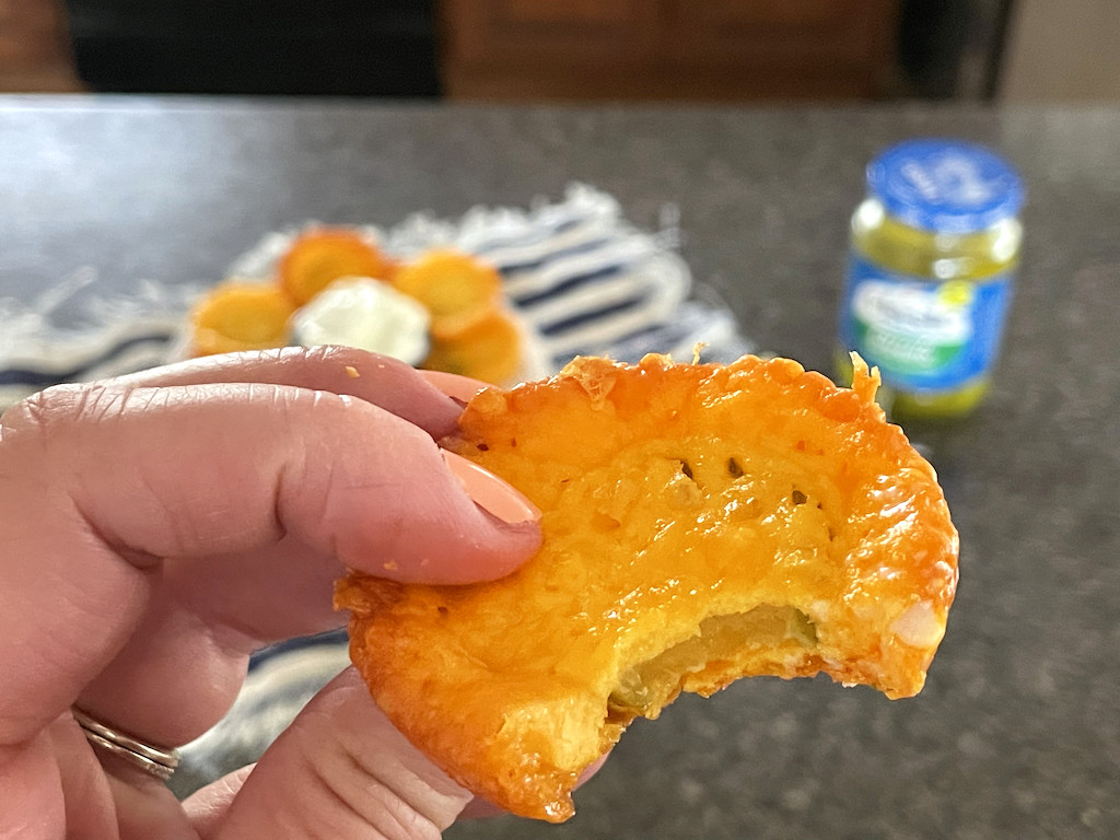 holding a keto cheese pickle chip with a bite taken out