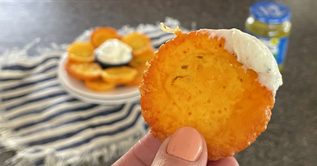 hand holding keto cheese pickle chips dipped in ranch